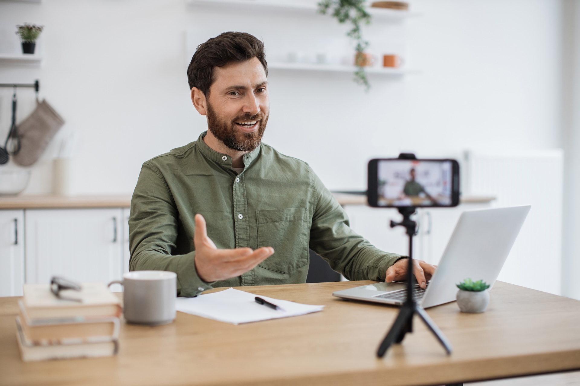 Man working on laptop and recording video on smartphone